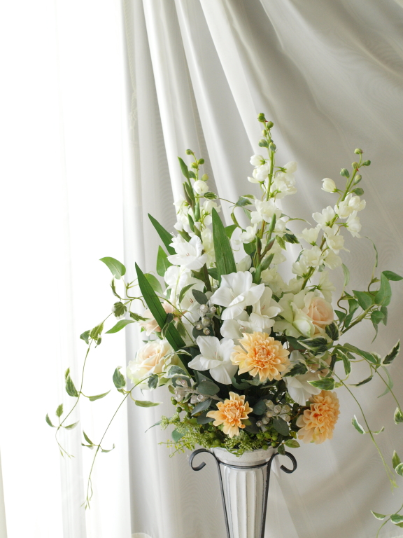高さのある花器にアレンジ　ご新居のお祝いに　白い花はストックです　縦のラインを生かしています